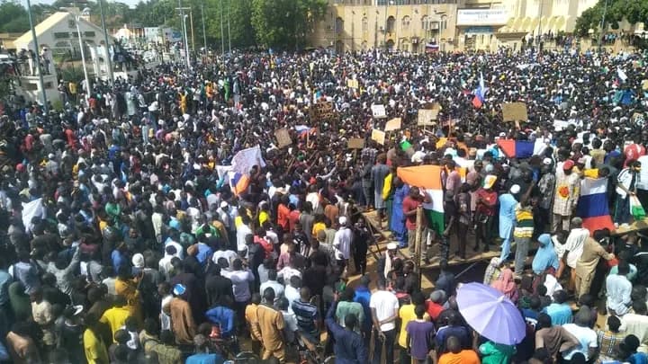 Marche de soutien aux putschistes à Niamey, foule rassemblée avec des drapeaux et pancartes.