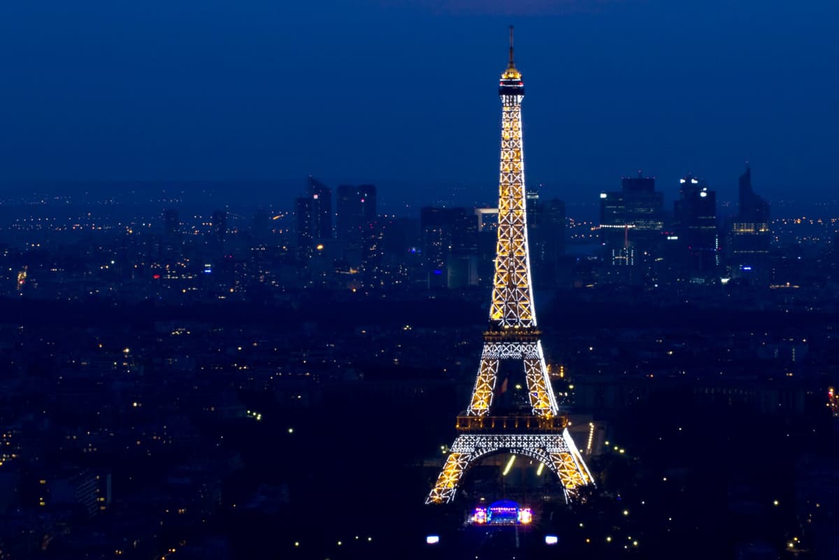 Tour Eiffel illuminée avec le quartier d'affaires de La Défense en arrière-plan, lors du 14 juillet à Paris.